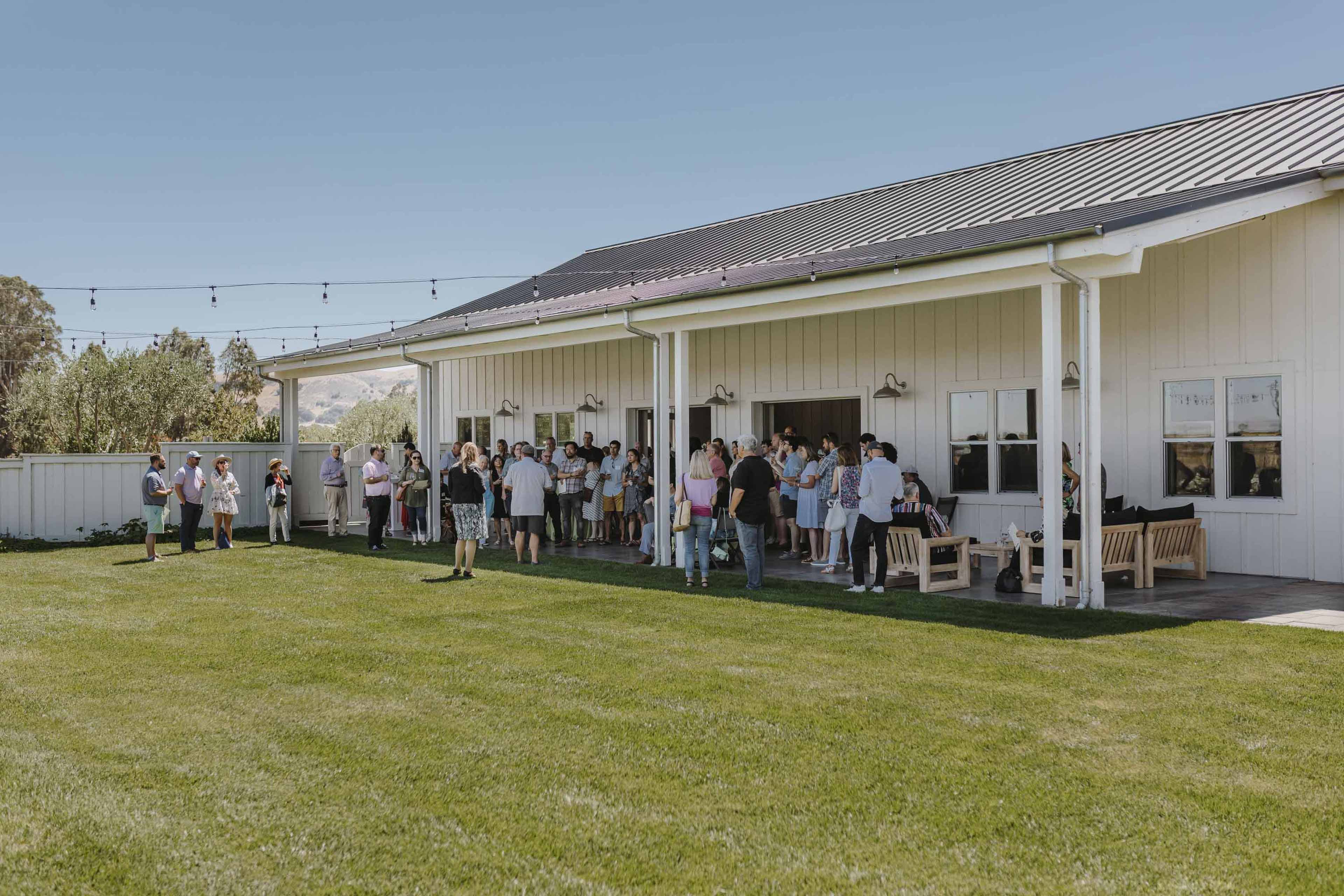 corporate event people hanging out in the barn and the lawn paying attentoin to a speaker